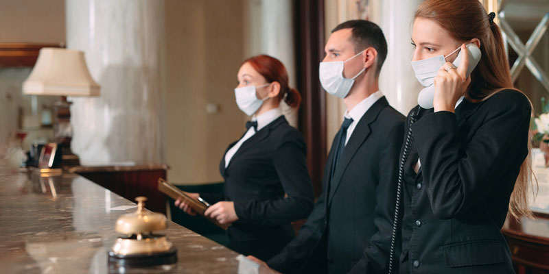 Hotel workers wearing masks during the pandemic at the check in desk in hotel the lobby.