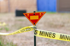 land mine warning sign with yellow tape showing the boundary of a mine field.