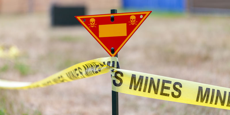 land mine warning sign with yellow tape showing the boundary of a mine field. 