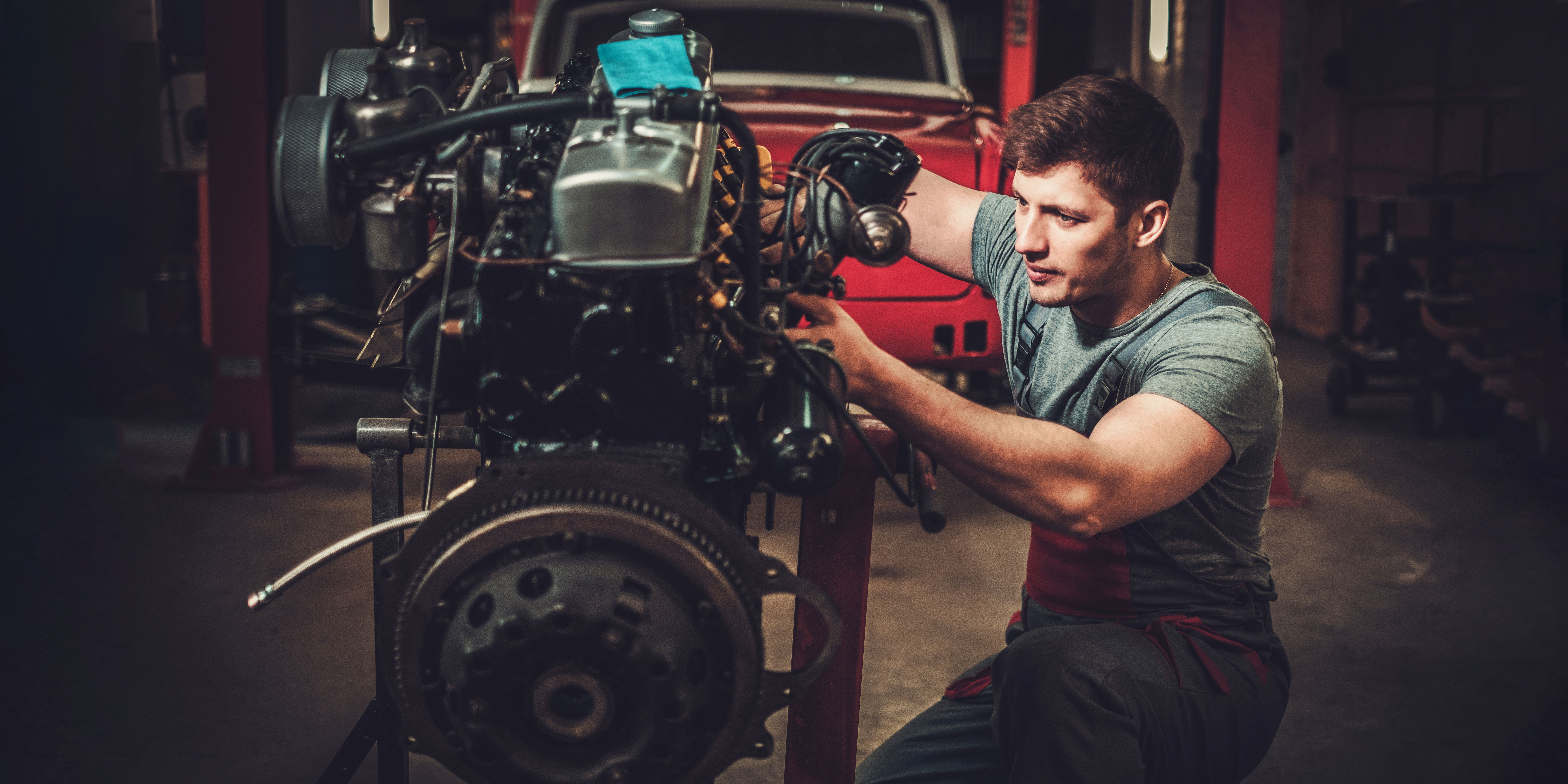 A male mechanic working on a car engine. 