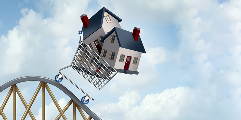 Illustration of a shopping cart full of houses going down the top of a roller coaster against a blue sky full of white fluffy clouds.